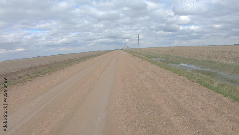 Point of view driving on a gravel road and thru and railroad crossing; rural Nebraska on a cloudy winter day; lonely road