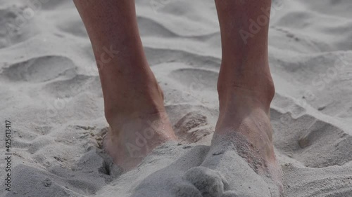 A woman hides her feet in the sand on the beach to hide athlete's foot .Shame coused by Fungal infection of the skin. photo