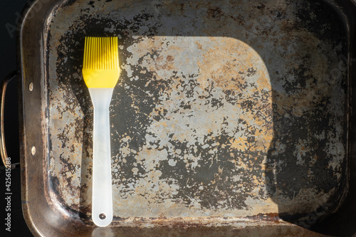 Culinary yellow silicone dough brush with a plastic handle on the background of an old shabby iron brush in bright sunlight. photo