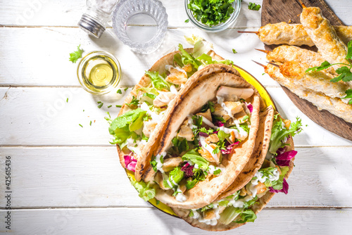 Mediterranean food. Doner Kebap, Taco, Shawarma, greek wrapped gyros sandwich, tortilla pita bread stuffed grilled chicken meat, fresh vegetables, tsatziki sauce. Sunny white wooden table copy space photo