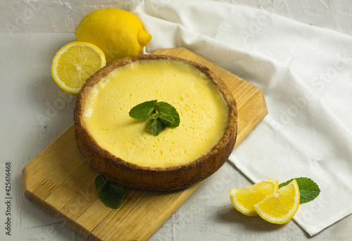 Traditional French Lemon Tart. Homemade pie dessert. Cake on wooden board and slice of fruit