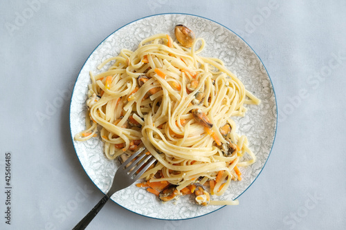 Linguini with mussels, carrot and cheese. Mediterranean pasta with seafood on a plate.