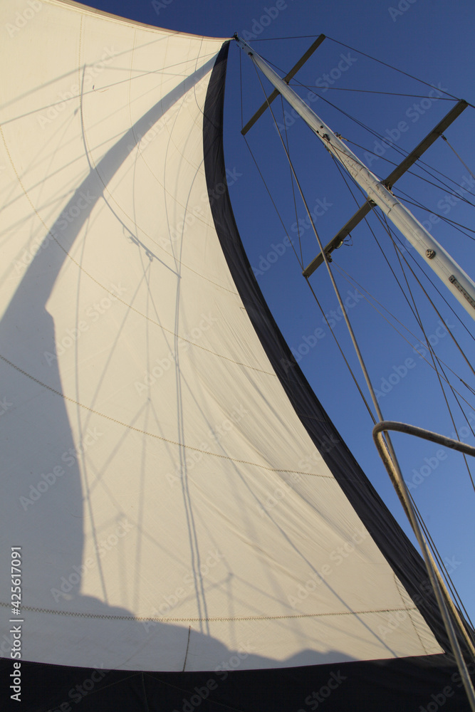 Big white sail with black stripes during sea walk in sunny day