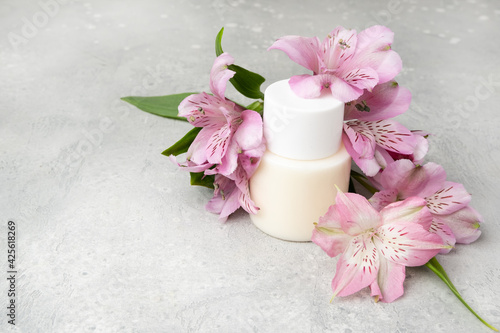 Cosmetics SPA branding mock-up. White cosmetic bottle containers with with pink exotic flowers on gray background. Natural organic beauty product concept  Minimalism style