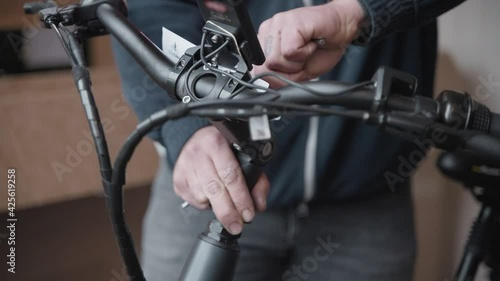 Man uses a allan key to set the height of the handles bars of a electric bike after adjusting the height of the steering shaft. photo