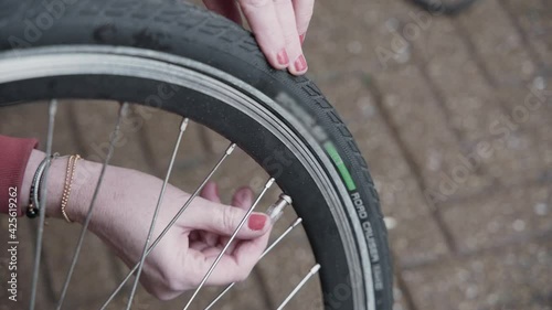 Lady adjusts the air pressure in her electric bike tires and installs the valve cap on the bike tire outside. photo