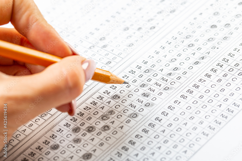The student fills in the answers to the test in the exercise and examination paper with a pencil. education concept. The student fills in the answers to the test in the exercise and examination paper with a pencil. education concept.