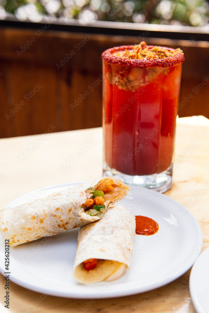 Mexican burrito and michelada beer with tomato juice with copy space