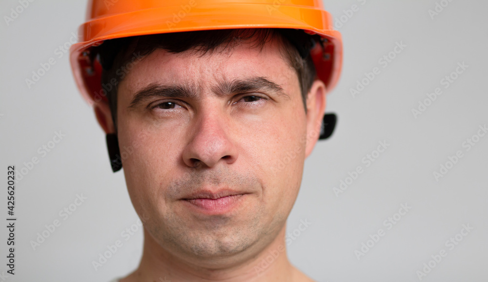 portrait of young construction worker in hard hat on grey studio background, frown face of engineer, portrait of young construction worker in hard hat on grey studio background, frown face of engineer,