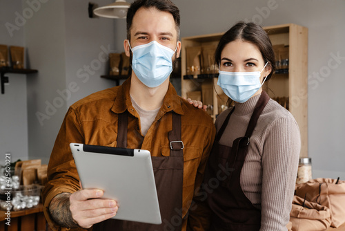 White sellers man and woman using tablet computer in eco shop