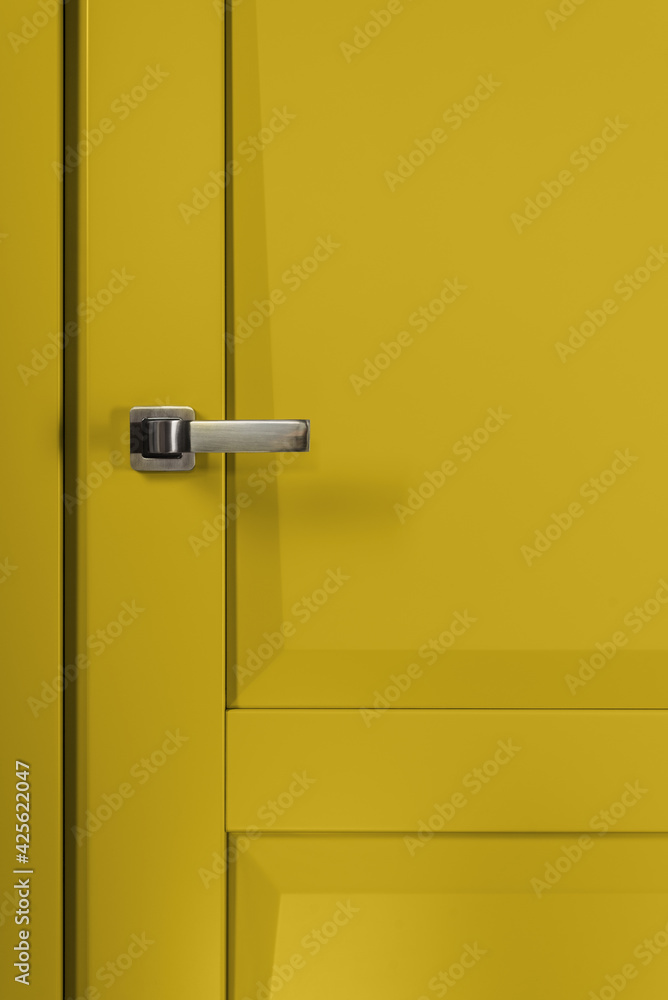 Stainless stylish door knob on yellow wooden door