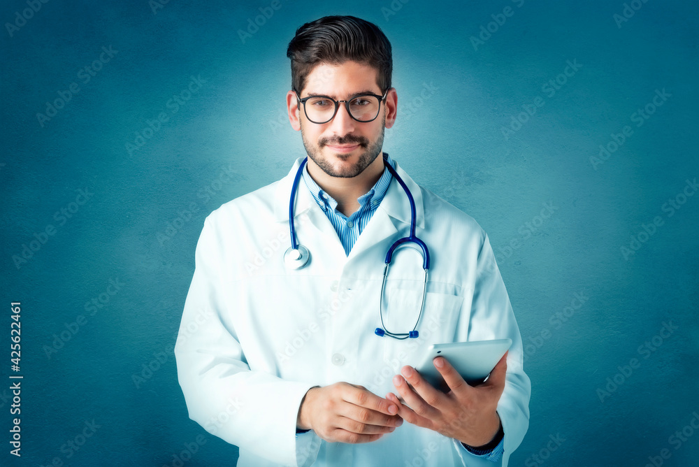 Male doctor holding touchpad in his hand while standing at isolated background Male doctor holding touchpad in his hand while standing at isolated background