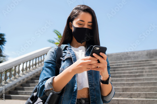Young woman using her mobile phone outdoors. © Mego-studio
