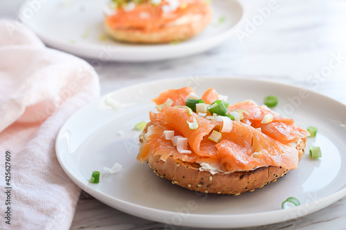 Smoked salmon sandwich on a bagel on white plate