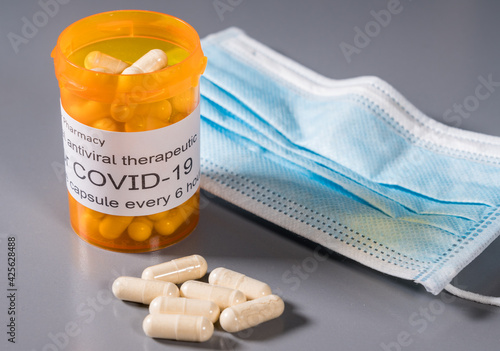 Prescription bottle and capsules illustrating trials of oral antiviral treatment for SARS-CoV-2 or Covid-19 virus