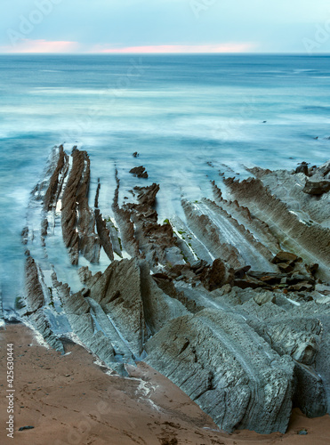 Twilight ocean coast with ribbed stratiform rock formations. (Atlantic Ocean, Spain).