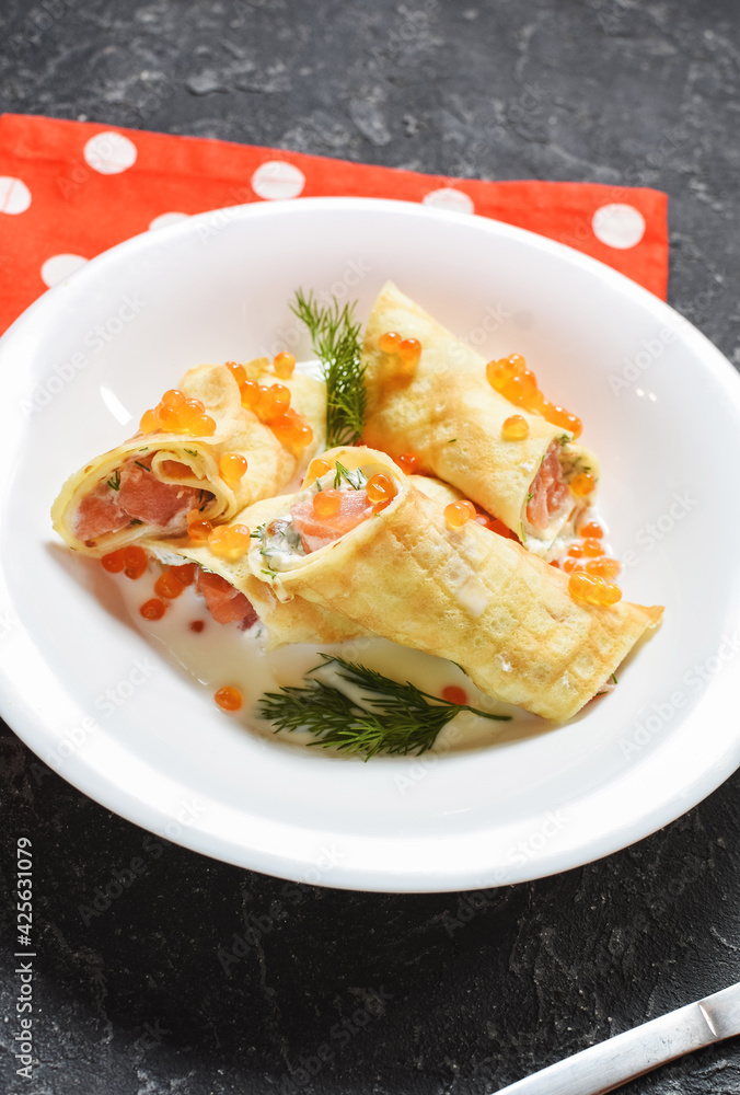 Delicious breakfast - crepes with smoked salmon, sour cream and caviarch on stone background. Delicious breakfast - crepes with smoked salmon, sour cream and caviarch on stone background.
