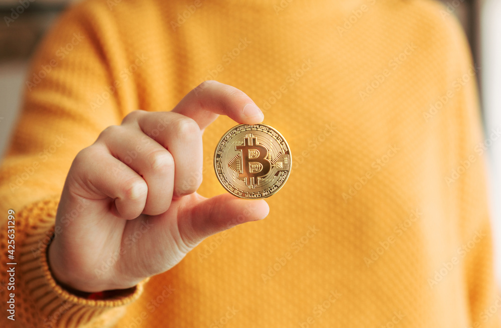 Woman showing a golden bitcoin in her hand. BTC and cryptocurrencies business in a digital decentralized finances concept Woman showing a golden bitcoin in her hand. BTC and cryptocurrencies business in a digital decentralized finances concept