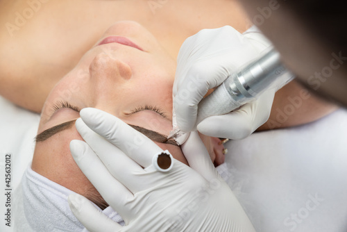 Konturowanie brwi, proces pigmentacji brwi. Kobieta w salonie urody w trakcie zabiegu, makijaż permanentny.  photo