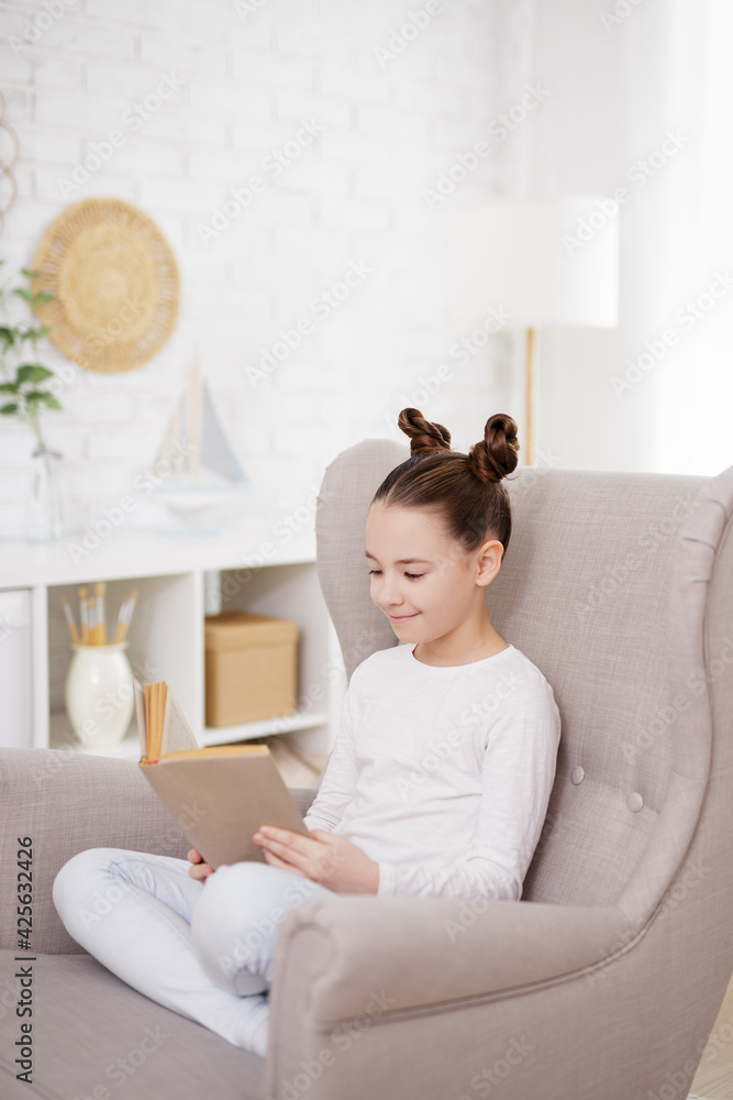 cute preteen girl reading book in bright living room cute preteen girl reading book in bright living room