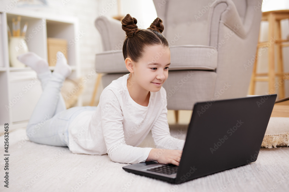 lifestyle, technology and online education concept - cute preteen girl using laptop at home lifestyle, technology and online education concept - cute preteen girl using laptop at home