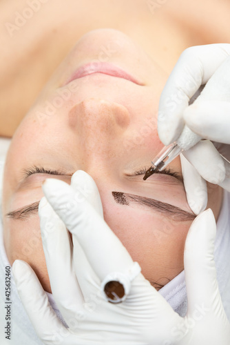 Zbliżenie na twarz kobiety w trakcie zabiegu makijażu permanentnego. Proces tatuowania brwi. 
