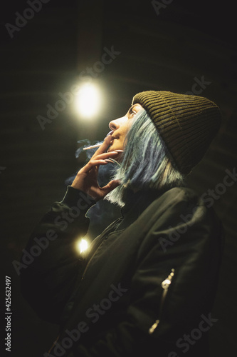 A girl smokes a cigarette on the street in an underground passage at night