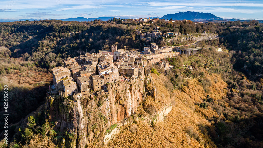 Postcard from Italy. Aerial view of the medieval village of Calcata with its volcanic cliff and the valley of the Treja river with Mount Soratte in the background.