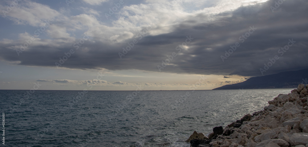 rocky and blue sea with mountain and dark clouds, bad weather