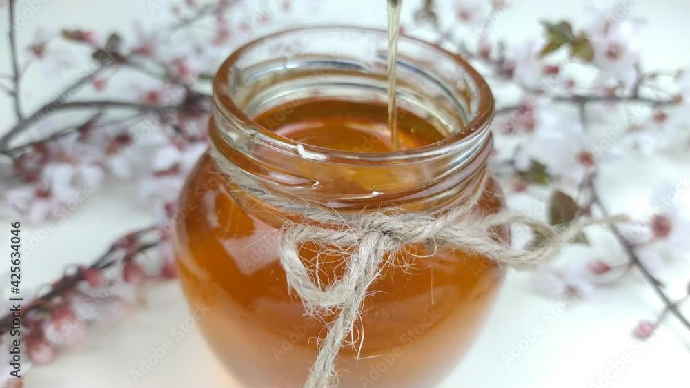 The glass bowl between the flowers is filled with honey, a source of energy and vitamins.energy.natural nutrition. The glass bowl between the flowers is filled with honey, a source of energy and vitamins.energy.natural nutrition.