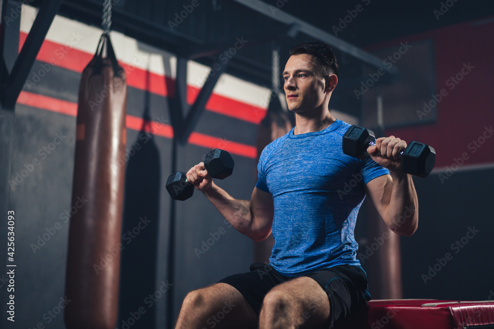 Sporty Caucasian man lifting dumbbell training for maintain muscle in fitness club or gym.