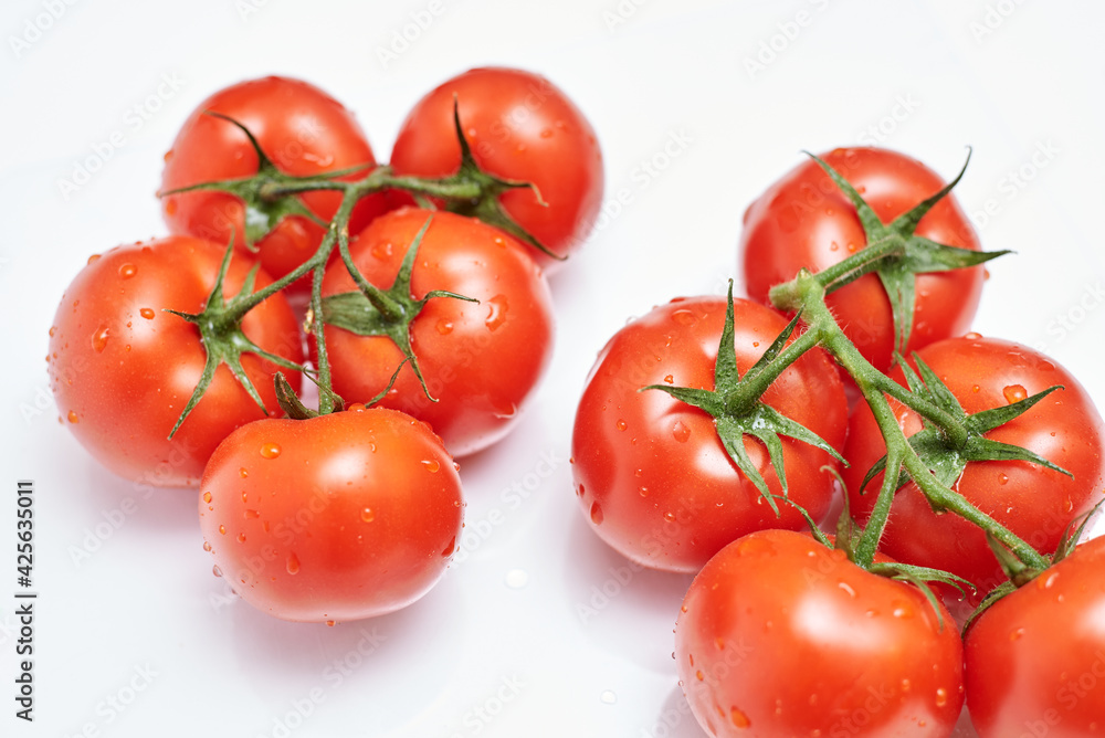 ripe tomatoes on a branch, white background