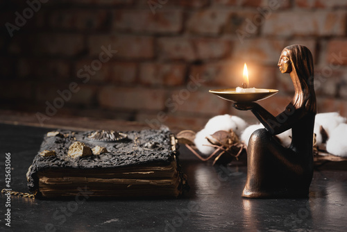 Ancient magic book and burning candle on the table close up. The witchcraft concept. photo