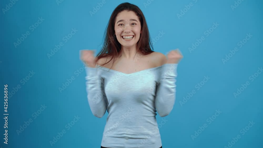 Shocked, happy Asian smiles. With dark hair, dressed in a blue blouse, isolated on a dark blue background in the studio Shocked, happy Asian smiles. With dark hair, dressed in a blue blouse, isolated on a dark blue background in the studio