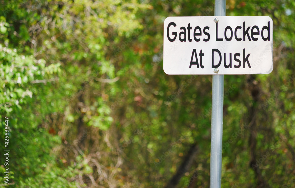 Notice Sign Warns of Gate Locking at Dusk
