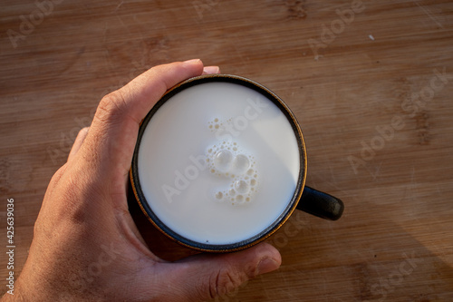 Glass of milk standing on old wooden table. Black glass with white milk. Black glass with white milk on the table