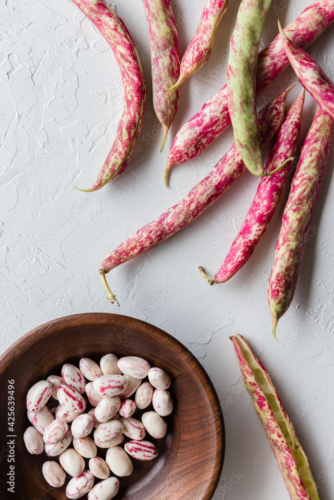Shelling Colorful Cranberry Borlotti Shell Beans with Wooden Bowl on White Background