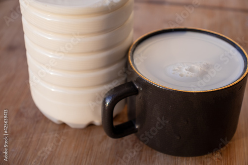 Glass of milk standing on old wooden table. Black glass with white milk. Black glass with white milk on the table