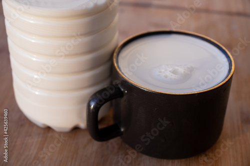 Glass of milk standing on old wooden table. Black glass with white milk. Black glass with white milk on the table