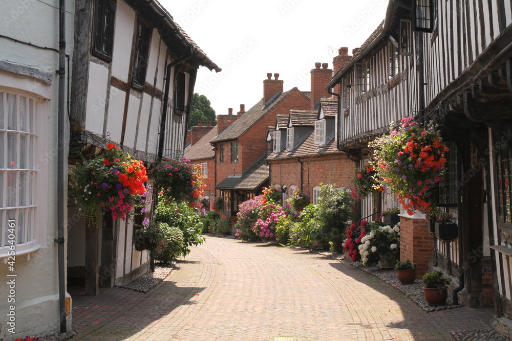 Half Timbered, Black & White Houses in Shakespeare's Country Malt Mill Lane Alcester Warwickshire, UK. Hanging baskets & floral blooms in High Summer.