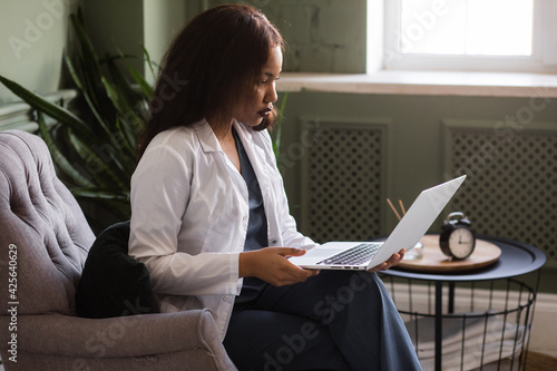 dark-skinned female doctor talking on Skype zoom with a laptop photo