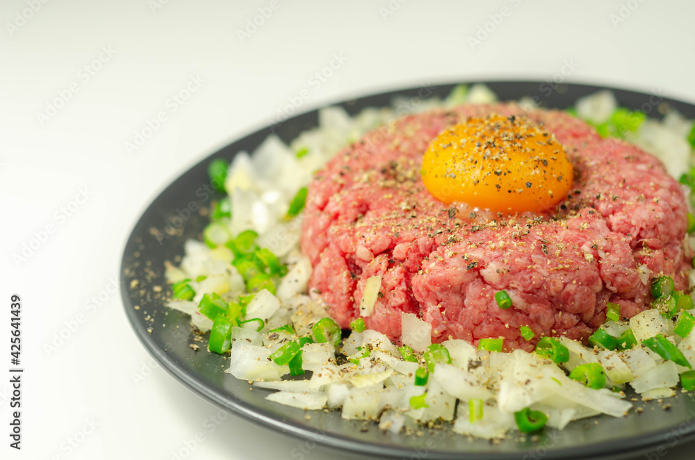 Beef steak tartare with raw egg yolk and onion with chive Beef steak tartare with raw egg yolk and onion with chive