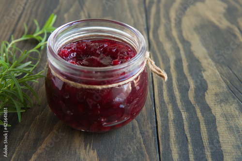 lingonberry sauce with rosemary in a glass jar on a dark wooden table