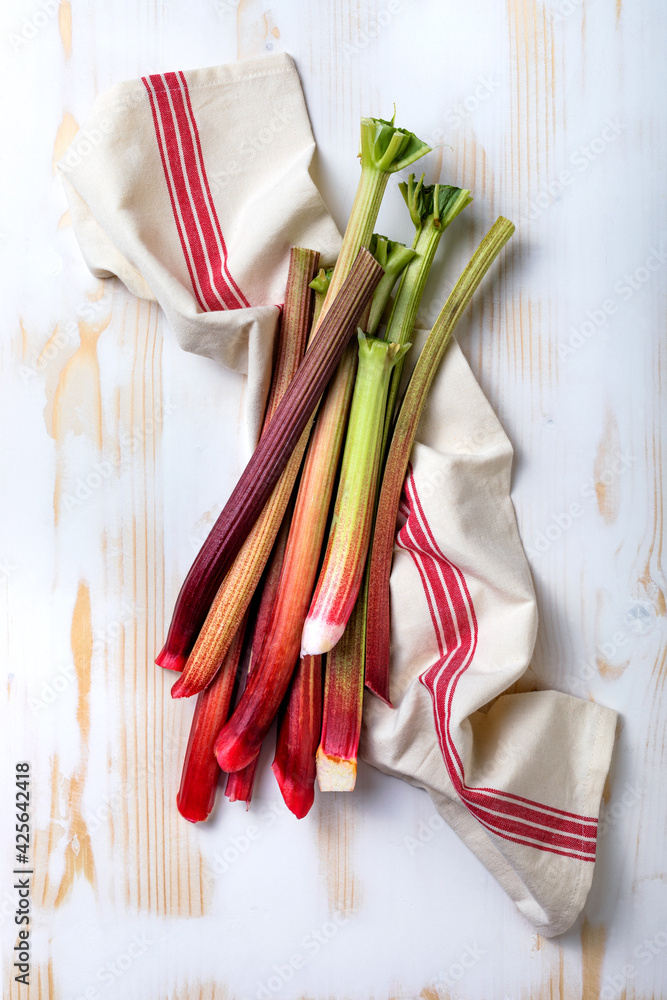Fresh organic red rhubarb on white wooden background. Bunch of fresh picked rhubarb stalks. Top view, copy space.