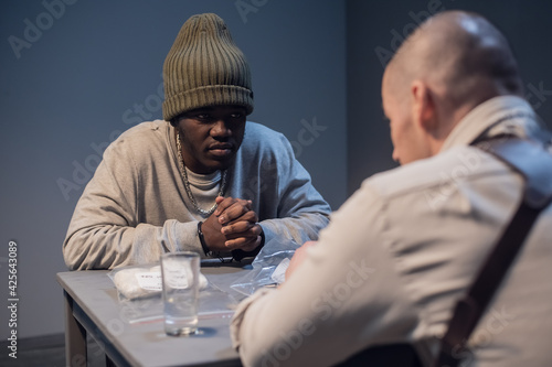Принти на полотні a black suspect in a hat under interrogation at the police station is worried in