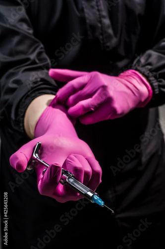 dentist posing with syringe, uniform, gloves, teeth and other instruments photo