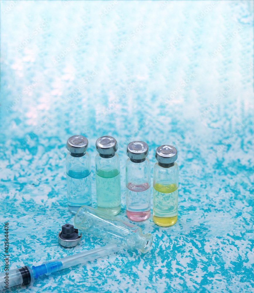 Medical ampoules, syringes and a mask on a green background. Vaccination against covid-19. Medical ampoules, syringes and a mask on a green background. Vaccination against covid-19.