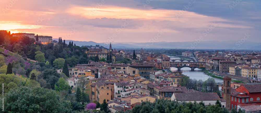 Panoramic view of Florence at sunset with in the background, the Basilica di Santo Spirito and its spire, the Church of San Frediano in Cestello and Ponte Vecchio.