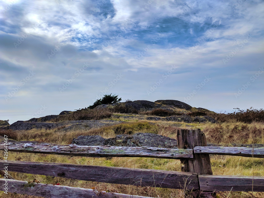 a wood fence at the top of a hill by the ocean side