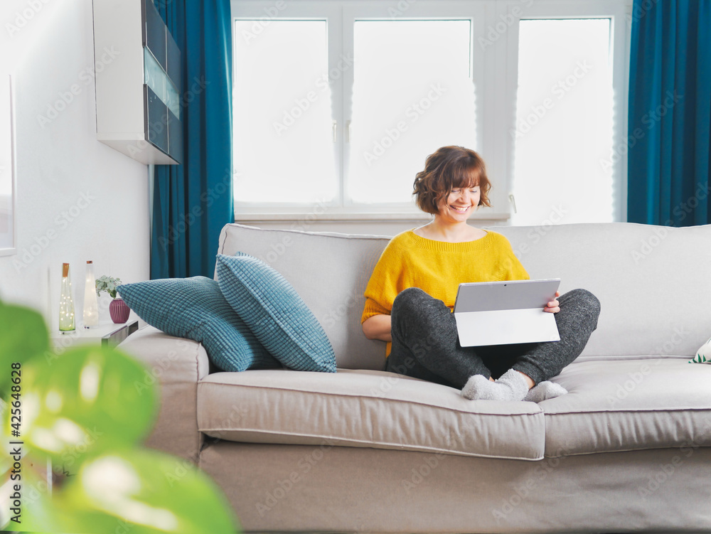 Smiling girl sit relax on couch using modern laptop.happy young woman freelance work on computer from home. social-distancing and self-isolation concept. coronavirus stay home and online live. Smiling girl sit relax on couch using modern laptop.happy young woman freelance work on computer from home. social-distancing and self-isolation concept. coronavirus stay home and online live.